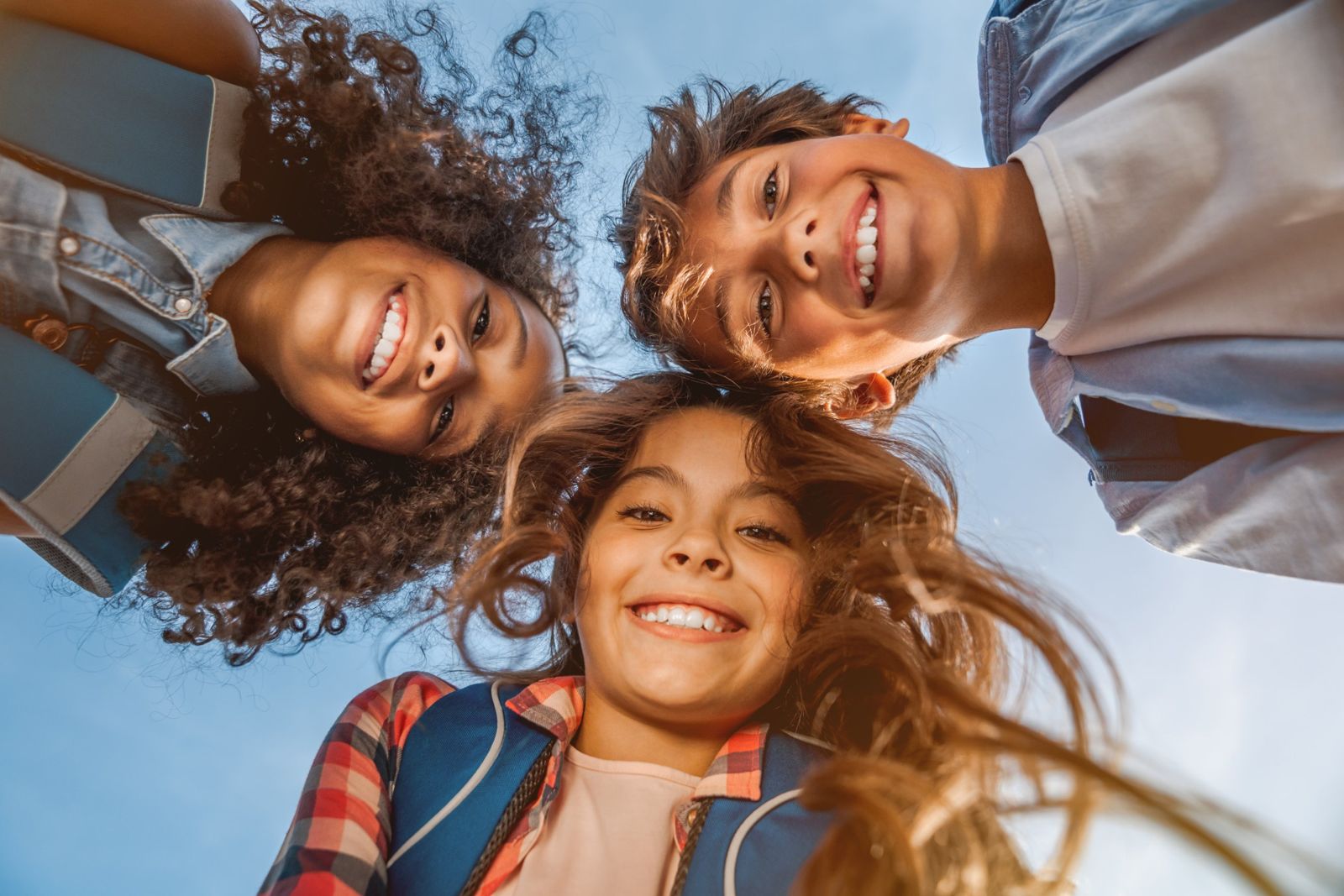 Three smiling kids looking down at the camera