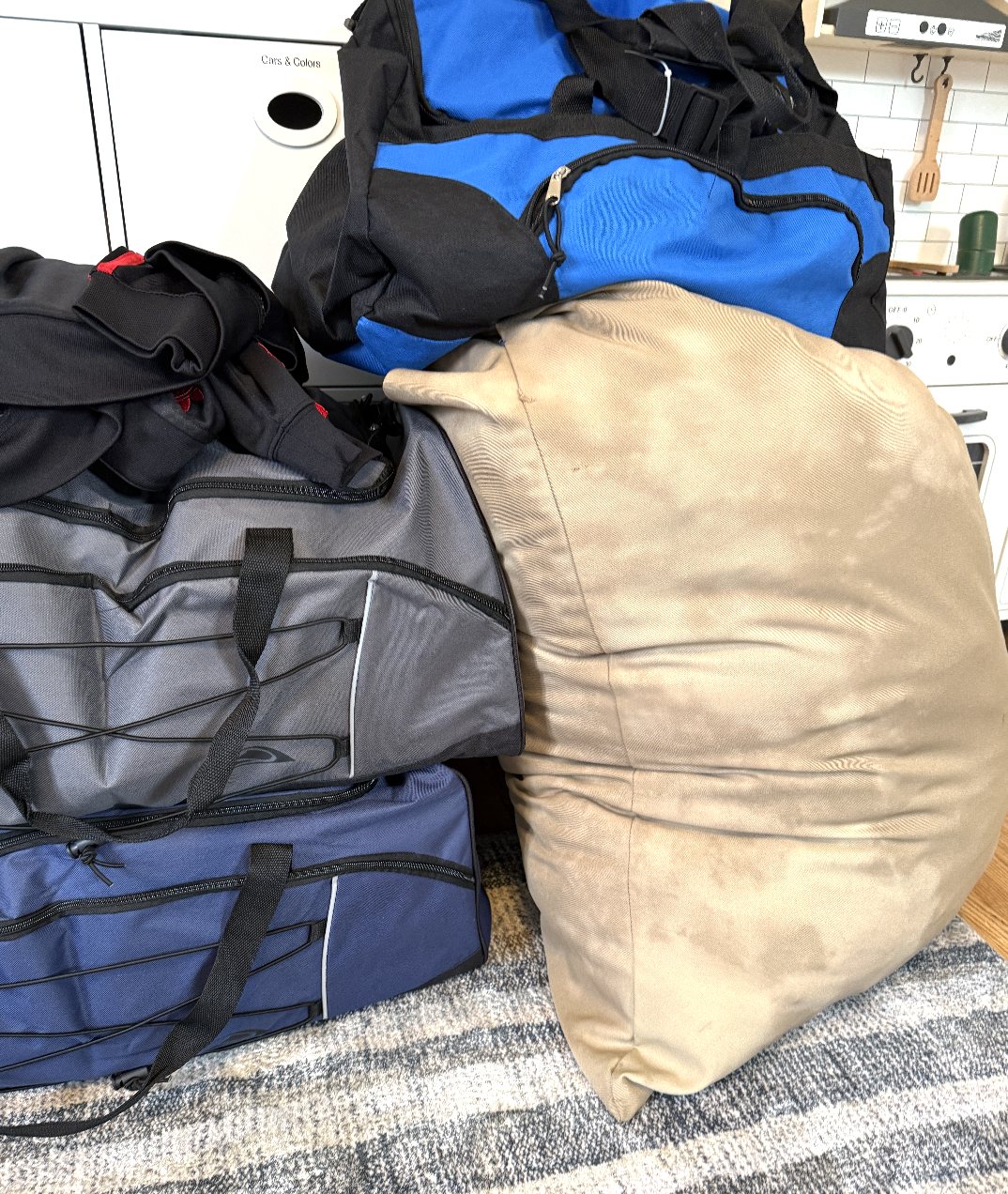 Packed duffel bags and a stuffed pillowcase waiting by the door