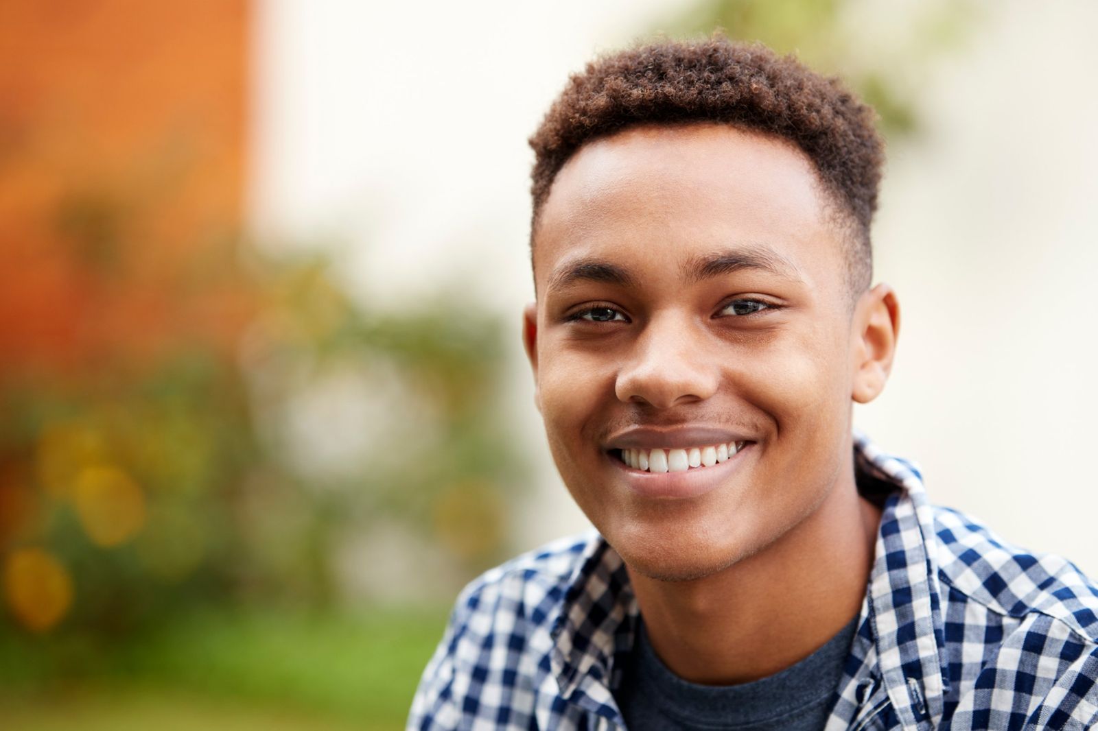 A smiling teenage boy in a checked shirt